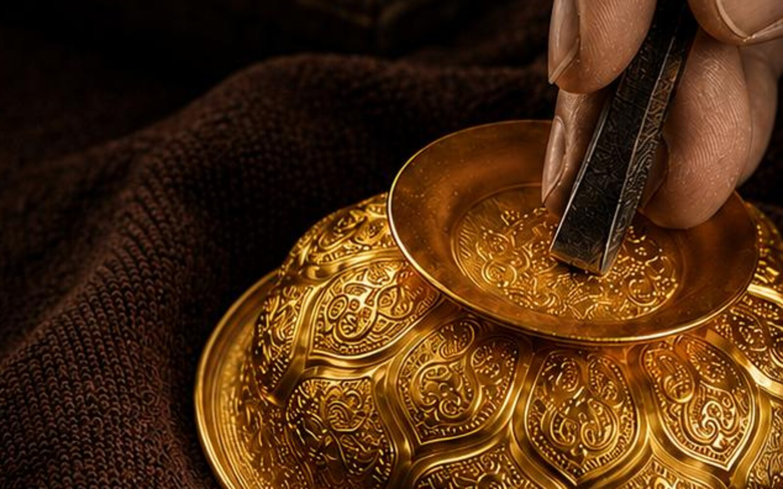 Artisan hand engraving a gold vessel